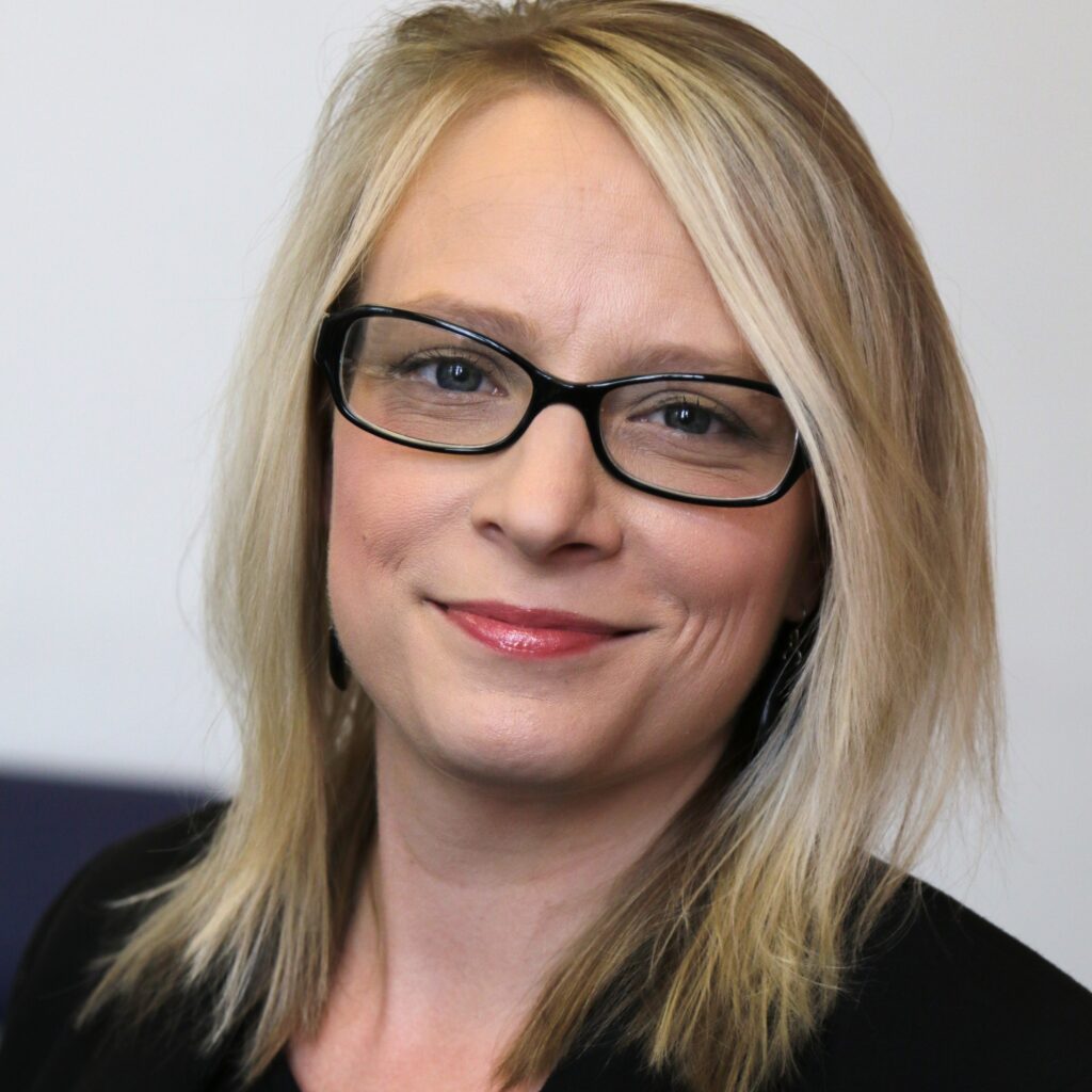 Stefanie Murray is a blonde woman with glasses wearing a black top.